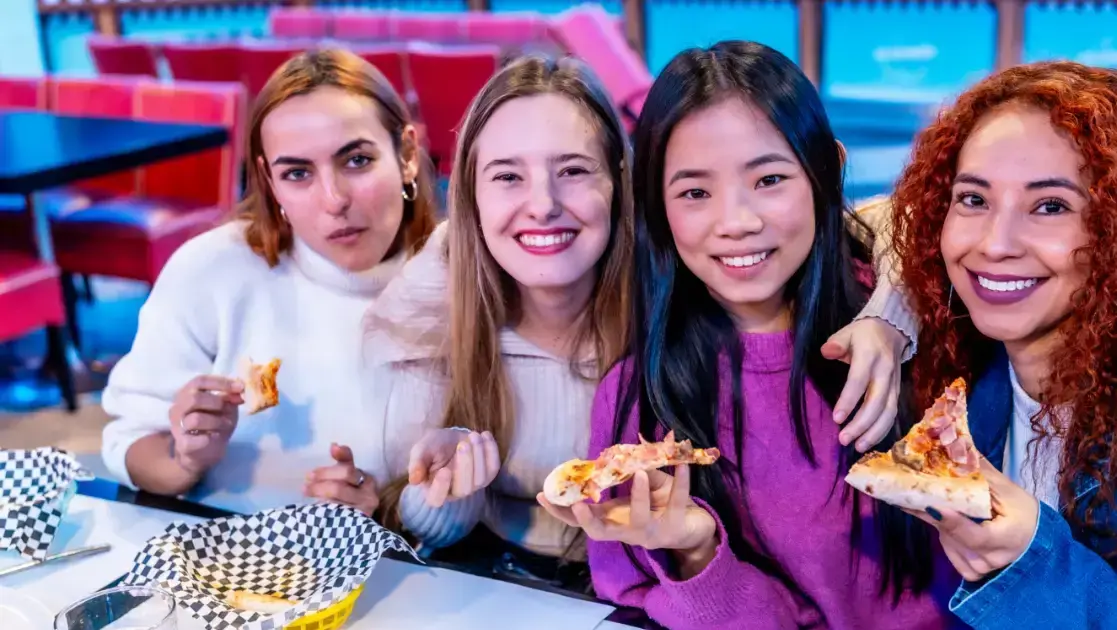 cheerful multiethnic female friends enjoying pizza e1782748558700