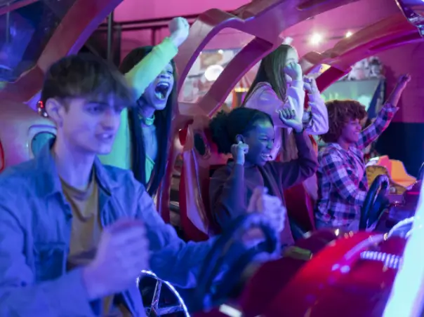 excited friends playing arcade racing game together